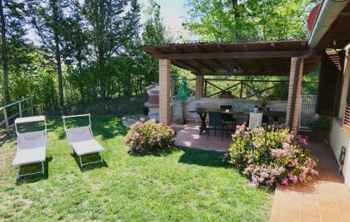 een achtertuin met 2 stoelen en een tafel en een pergola bij ISA-Chalet Elena in Montescudaio, with air conditioning, on the ground floor with fenced garden in Montescudaio