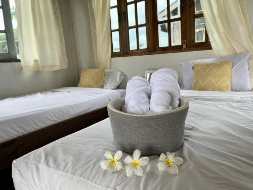 a basket of towels sitting on a bed with flowers at Dee Tor Jai Farm Stay ดีต่อใจฟาร์มสเตย์ in Chiang Klang