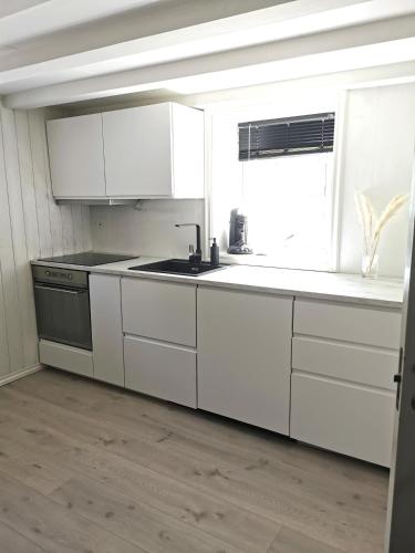 a kitchen with white cabinets and a sink and a window at Cozy apartment near city centre in Stavanger