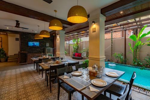 a restaurant with tables and chairs and a swimming pool at Riva Gold Coast in Candolim