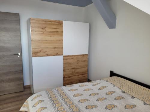 a bedroom with a bed and a wooden door at LUCA tetőtéri Apartman in Pápa