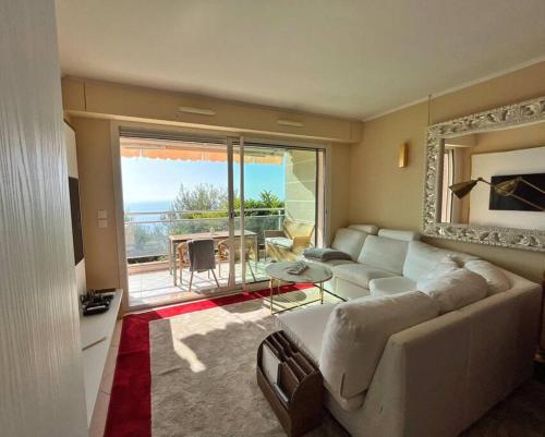 - un salon avec un canapé blanc et une grande fenêtre dans l'établissement Les Jardins de Monaco vue mer et piscine, à Saint-Antoine