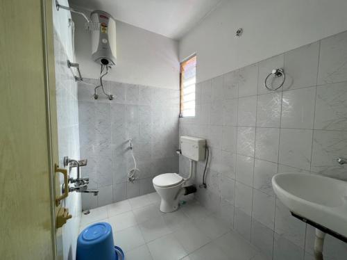 a white bathroom with a toilet and a sink at Hotel Tashi Ga Tsel in Tawang