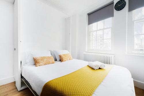 a bedroom with a bed with a yellow blanket at Hyde Park Apartments in London