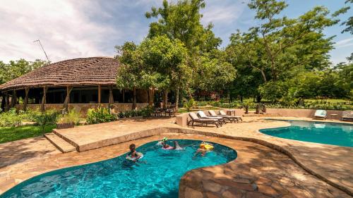 a swimming pool with two people in the water at Sambiya River Lodge in Murchison Falls National Park