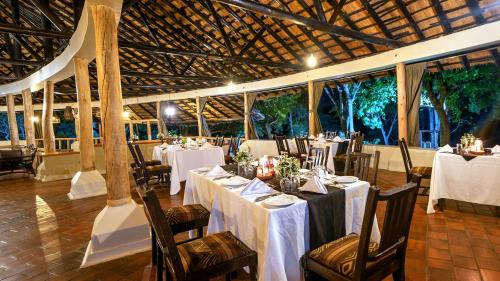 a dining room with white tables and chairs in a building at Sambiya River Lodge in Murchison Falls National Park