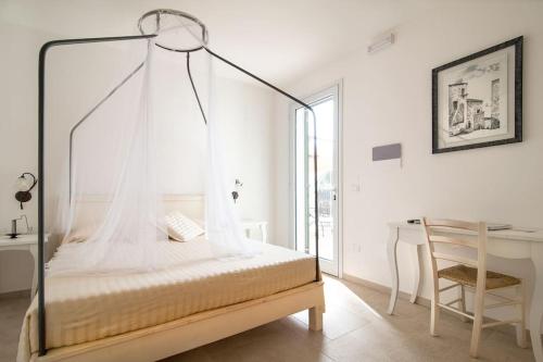 Agriturismo Fontanelle في أوترانتو: غرفة نوم مع سرير المظلة ومكتب