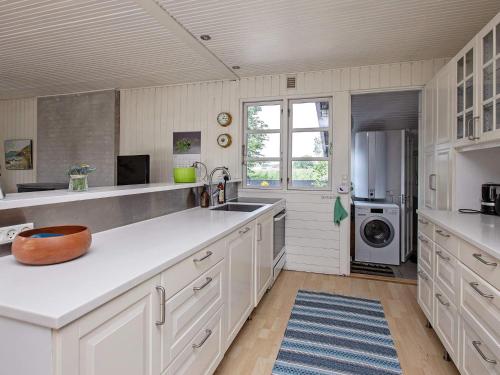 uma grande cozinha com armários brancos e um frigorífico em 6 person holiday home in Mern em Mern