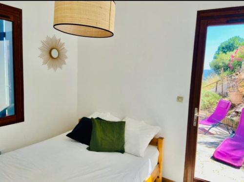 1 dormitorio con cama y ventana con sillas rosas en CAVALOC T2 terrasse vue colline en Cavalaire-sur-Mer