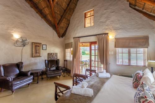 a living room with a bed and a couch and chairs at Aquila Private Game Reserve & Spa in Touwsrivier