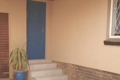 a porch with a blue door and a potted plant at Blue Door in Boksburg