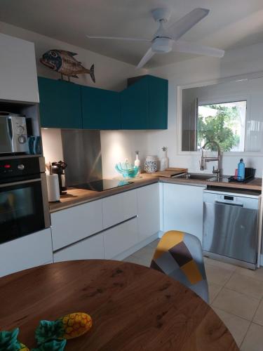 a kitchen with white cabinets and a wooden table at villa dans lo in Le Moule