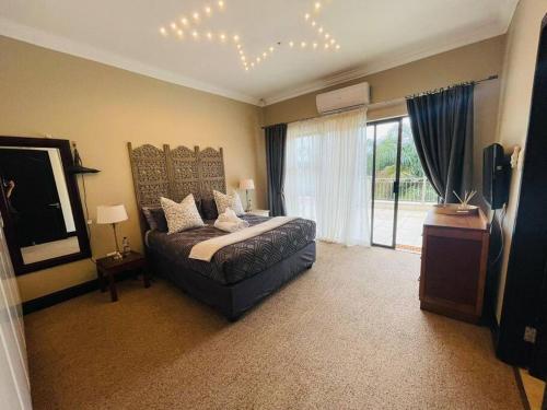 a bedroom with a bed and a large window at Palms On Byrne: Where Elegance Meets Serenity in Durban