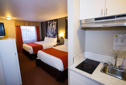 a hotel room with two beds and a kitchen at Super 8 by Wyndham Drayton Valley in Drayton Valley