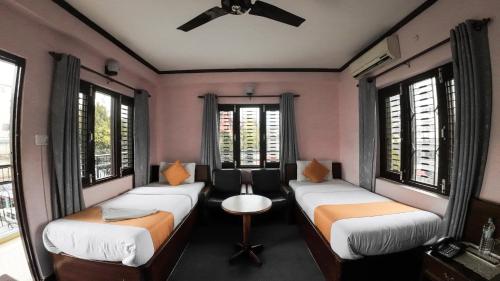 2 bedden in een kamer met ramen en een plafondventilator bij Hotel Travel Inn in Pokhara