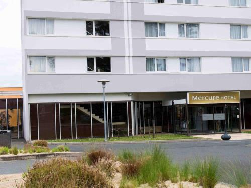 un gran edificio blanco con un cartel delante en Hotel Mercure Angers Lac De Maine, en Angers