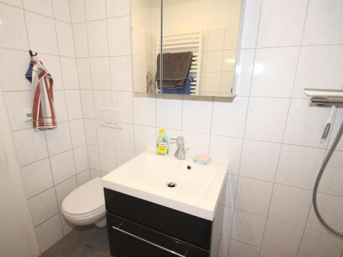 ein Badezimmer mit einem Waschbecken, einem WC und einem Spiegel in der Unterkunft Bungalow, Berumburg in Berumbur