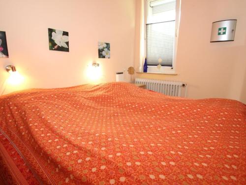 1 dormitorio con 1 cama con colcha de color naranja en Bungalow in Berumbur nahe Norddeich Strand, en Berumbur