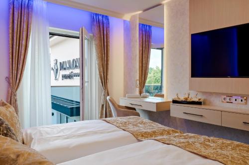 a hotel room with two beds and a flat screen tv at Diamond Panzió in Hajdúszoboszló