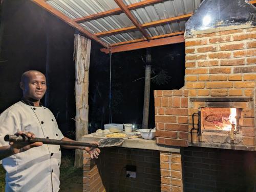 a man standing in front of a brick oven at Mvuli Hotels Arusha in Arusha