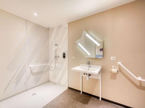 La salle de bains est pourvue d'une douche et d'un lavabo. dans l'établissement ibis budget Versailles - Trappes, à Trappes