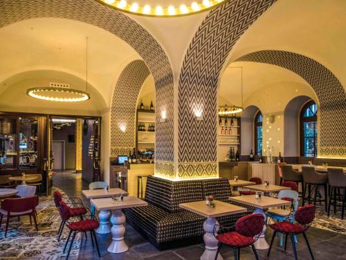 un restaurante con mesas y sillas y un bar en Mercure Vienna First en Viena