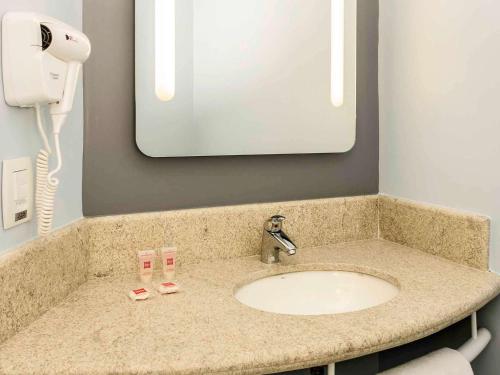 a bathroom counter with a sink and a mirror at ibis Manaus Aeroporto in Manaus