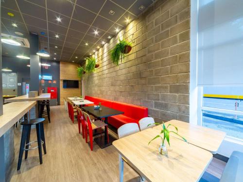 a restaurant with red chairs and tables and a brick wall at ibis Manaus Aeroporto in Manaus