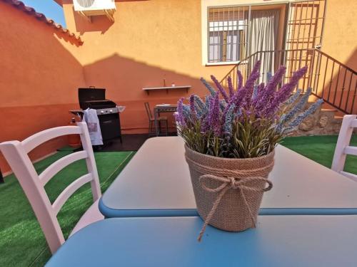 una mesa con un jarrón de flores púrpuras. en El Nido VUT, en Polán