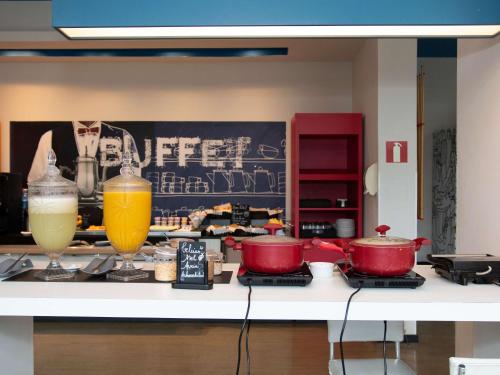 a kitchen counter with two drinks and pots and pans at ibis budget Manhuaçu in Manhuaçu