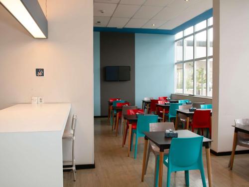 a dining room with tables and colorful chairs at ibis budget Manhuaçu in Manhuaçu