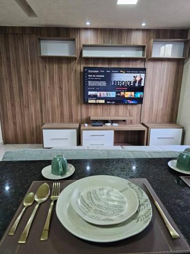 mesa con platos y utensilios y TV en 204 - Loft de luxo com Alexa e Ar condicionado, en Belo Horizonte
