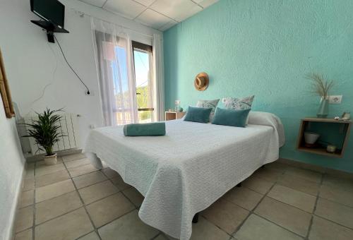 Schlafzimmer mit einem Bett mit blauen Wänden und einem Fenster in der Unterkunft La Puerta Azul in Jávea