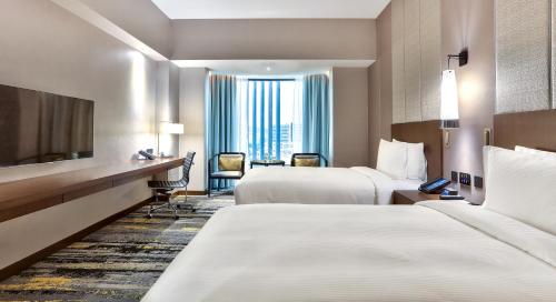 a hotel room with two beds and a television at Hilton Kota Kinabalu in Kota Kinabalu