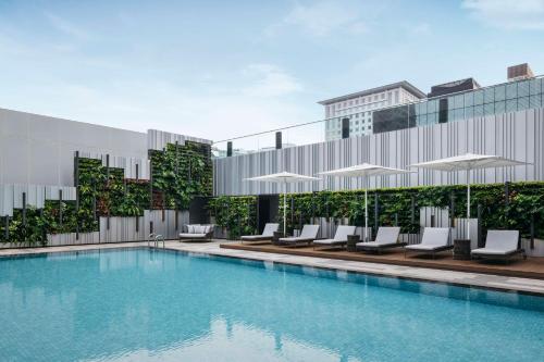 新加坡的住宿－Hilton Singapore Orchard，一座带椅子和遮阳伞的游泳池位于一座建筑旁边