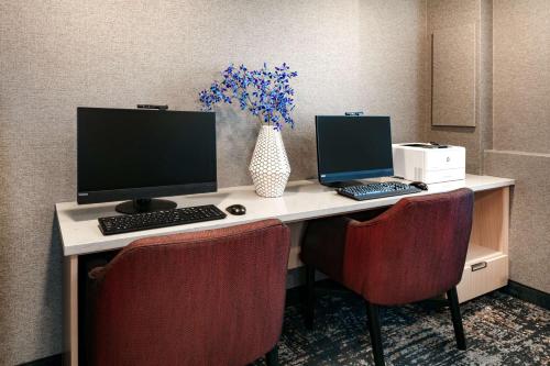 a desk with two computers and a vase of flowers at Hyatt Place Fairbanks in Fairbanks