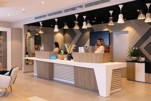 a woman talking on a cell phone at a counter at Hilton Garden Inn Le Havre Centre in Le Havre