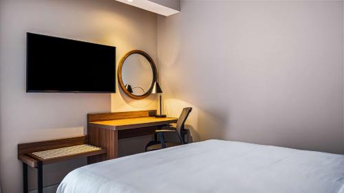 a bedroom with a bed and a desk with a mirror at Hampton Inn By Hilton Nuevo Vallarta in Nuevo Vallarta 