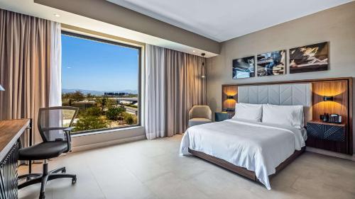 ein Schlafzimmer mit einem Bett und einem großen Fenster in der Unterkunft Hampton Inn By Hilton Nuevo Vallarta in Nuevo Vallarta