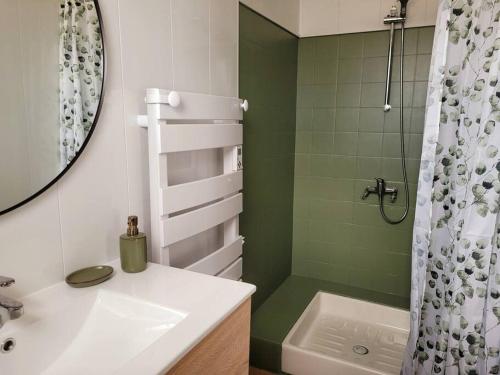 La salle de bains est pourvue d'un lavabo blanc et d'une douche. dans l'établissement Gîte Moussette - Bord de Mer - 4/6 pers., à Quinéville