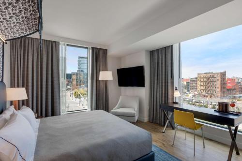 ボストンにあるCanopy By Hilton Boston Downtownのベッド、デスク、窓が備わるホテルルームです。
