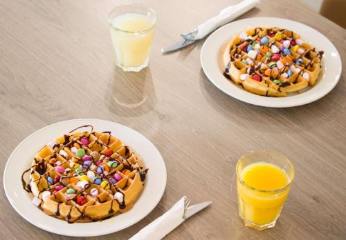two plates of waffles on a table with two glasses of orange juice at Hampton By Hilton Bath City in Bath