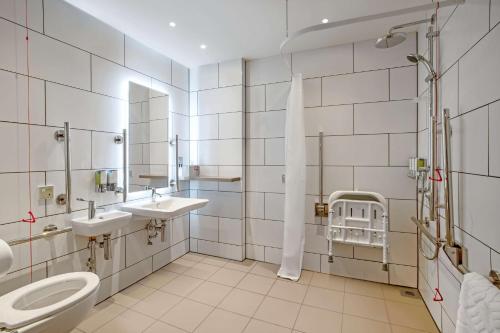 a bathroom with a toilet and two sinks and a mirror at Hampton By Hilton Bath City in Bath