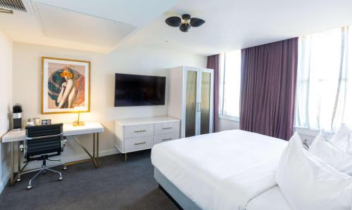 ein Hotelzimmer mit einem Bett, einem Schreibtisch und einem TV in der Unterkunft The Kelly Birmingham, Tapestry Collection By Hilton in Birmingham