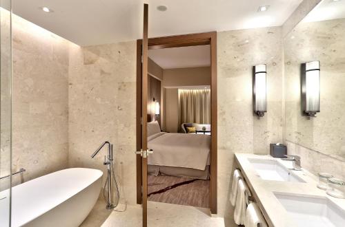 a bathroom with a bath tub and a bedroom at Hilton Kota Kinabalu in Kota Kinabalu
