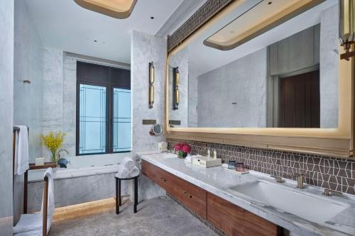 La salle de bains est pourvue d'un grand miroir et d'un lavabo. dans l'établissement Doubletree By Hilton Yancheng Dayangwan, à Yancheng