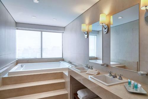a bathroom with two sinks and a bath tub at Hilton Porto Alegre, Brazil in Porto Alegre