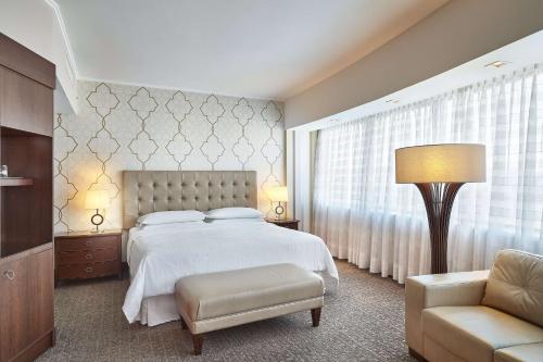 a bedroom with a bed and a chair and a lamp at Hilton Porto Alegre, Brazil in Porto Alegre