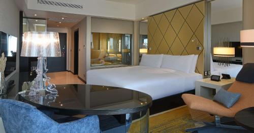 Hilton Amman في عمّان: غرفة فندقية بسرير وطاولة وكراسي