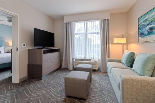 a living room with a couch and a tv at Homewood Suites By Hilton Panama City Beach, Fl in Panama City Beach